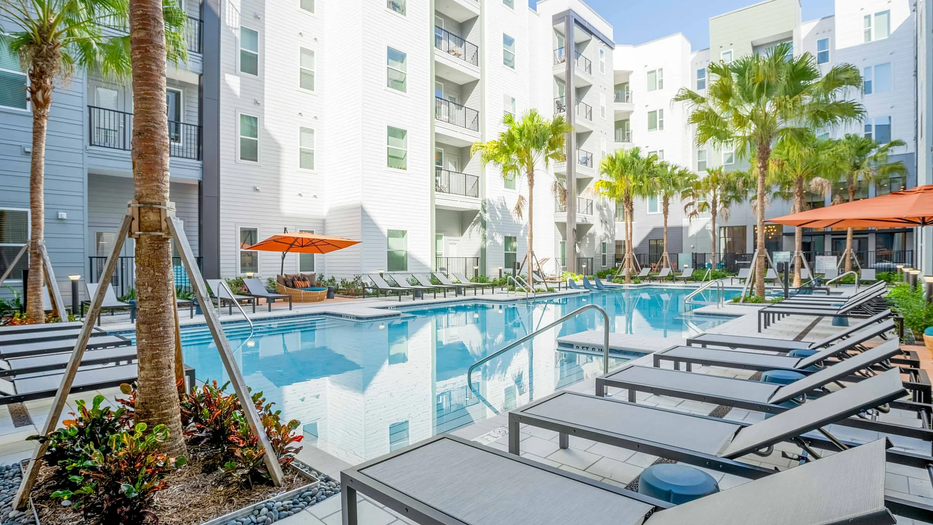 Sparkling pool with sun loungers and orange umbrellas lining the pools edge