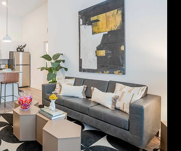 Model apartment living room with white walls and hardwood floors connected to the kitchen