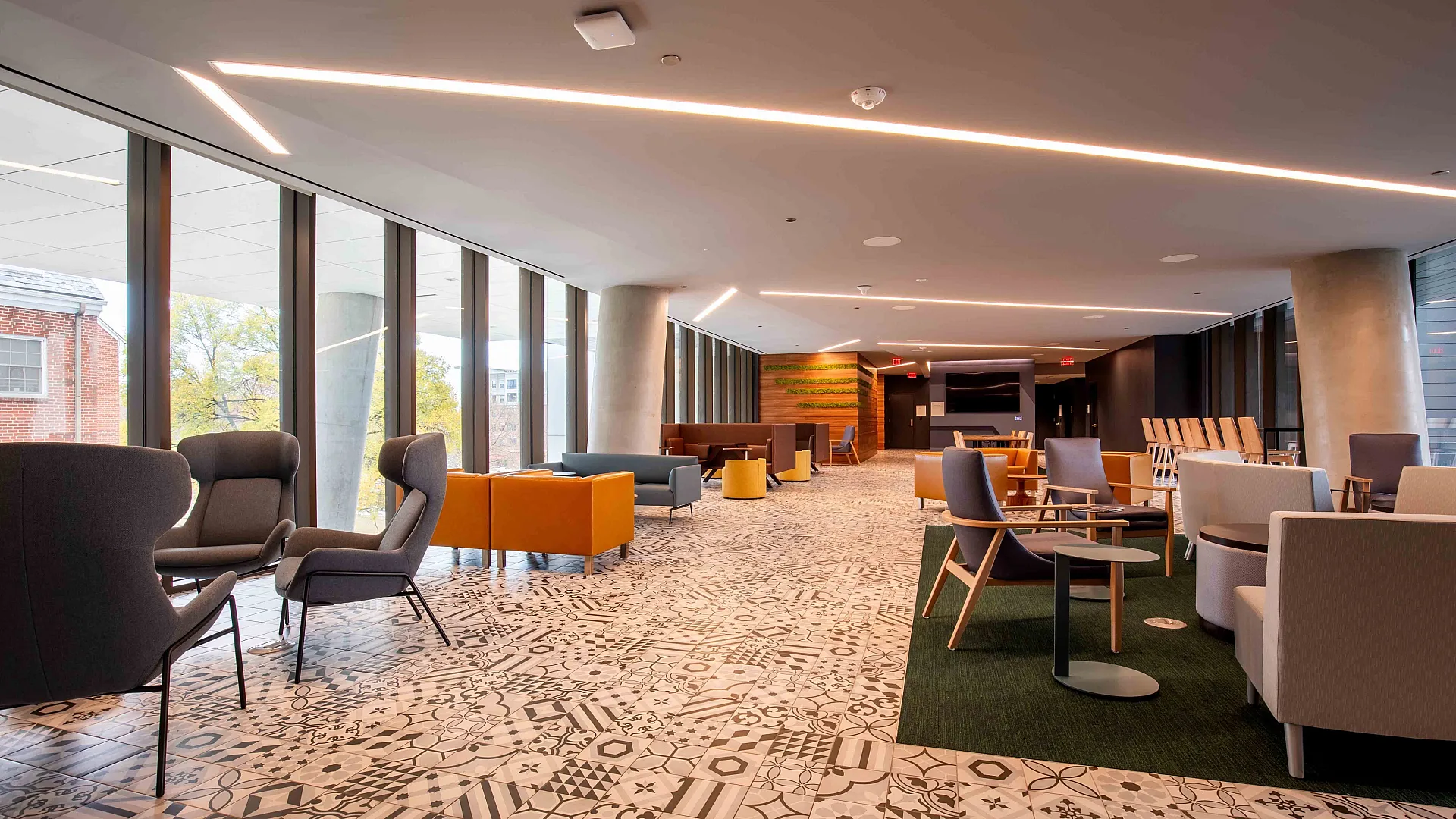 An interior view of a residential lounge at Union on Knox's apartments in College Park, MD featuring various tables, chairs, couches, decorative tile flooring, and a flatscreen television at the back wall end of the lounge.