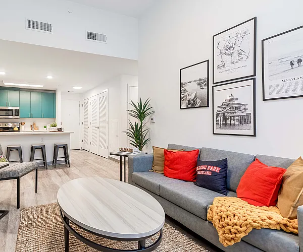 Model apartment living room with a couch and coffee table pointed at a flat screen tv