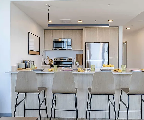 Model apartment kitchen with light cabinets, granite countertops, and stainless steel appliances