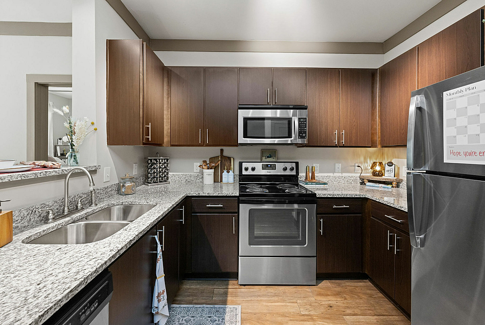 Modern kitchen with sleek stainless steel appliances, elegant dark wood cabinets, and granite countertops.