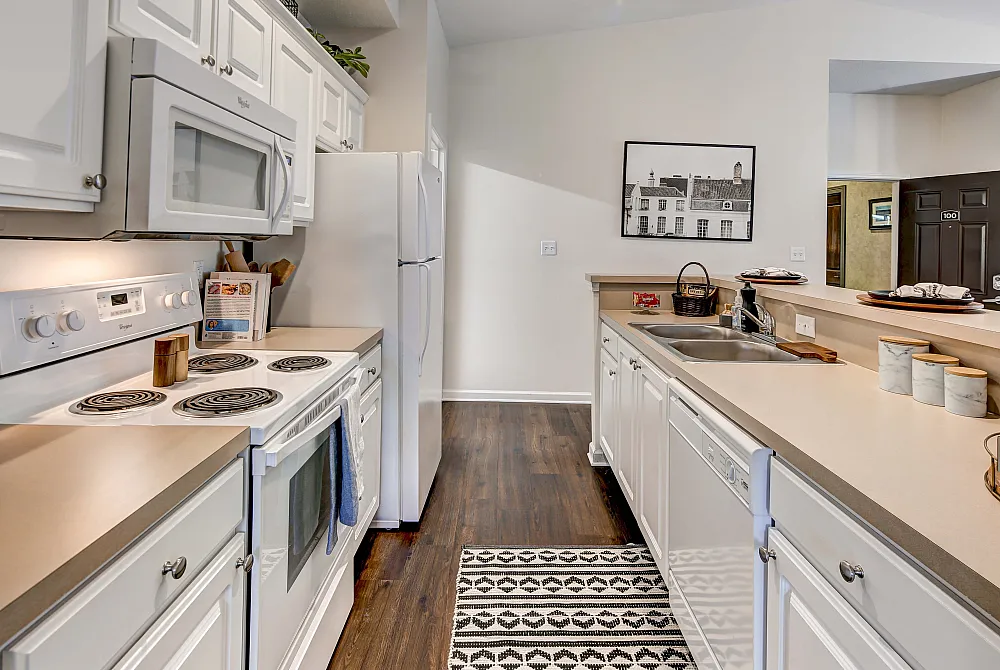 Charming kitchen with sleek white cabinetry, modern appliances, and elegant wood flooring, creating a warm and inviting culinary space.
