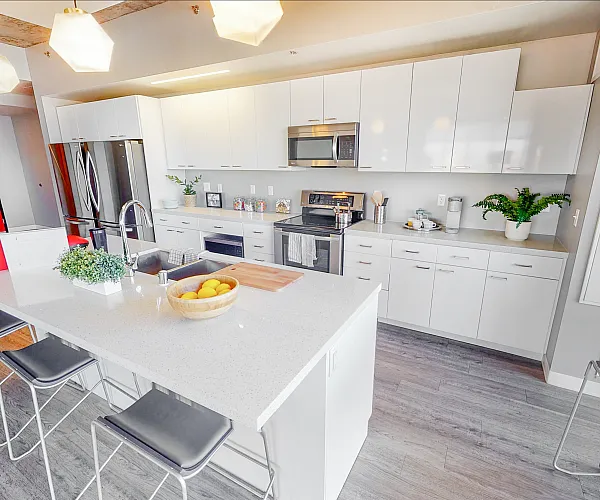 Contemporary kitchen with sleek white cabinets, modern appliances, and a spacious island with seating in a chic apartment.