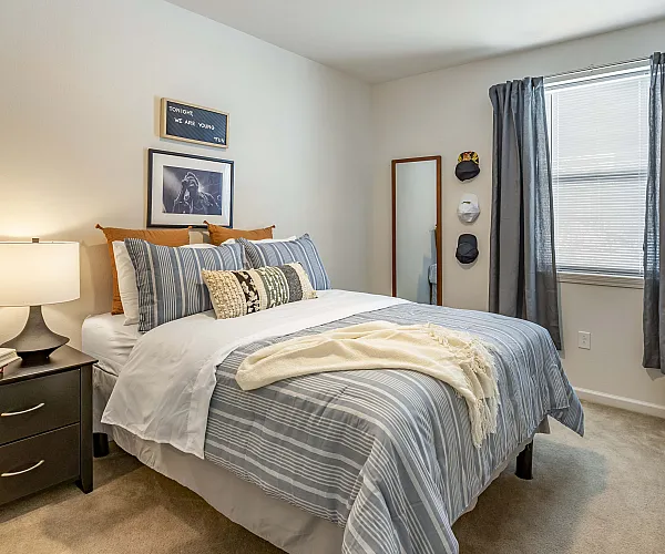 Cozy bedroom with stylish decor, featuring a plush bed with striped bedding, soft lighting, and elegant wall art creating a relaxing atmosphere.