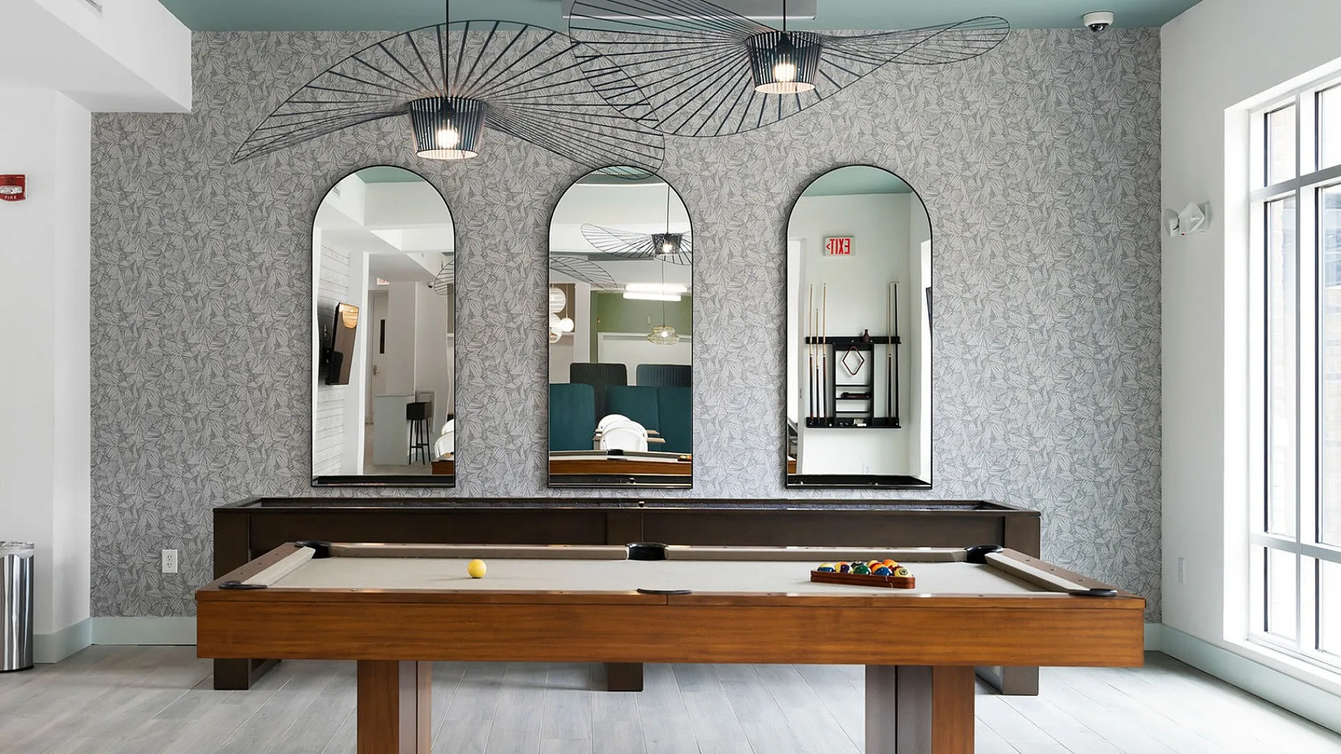 Elegant game room featuring a stylish billiards table, modern decor, and ample natural light.