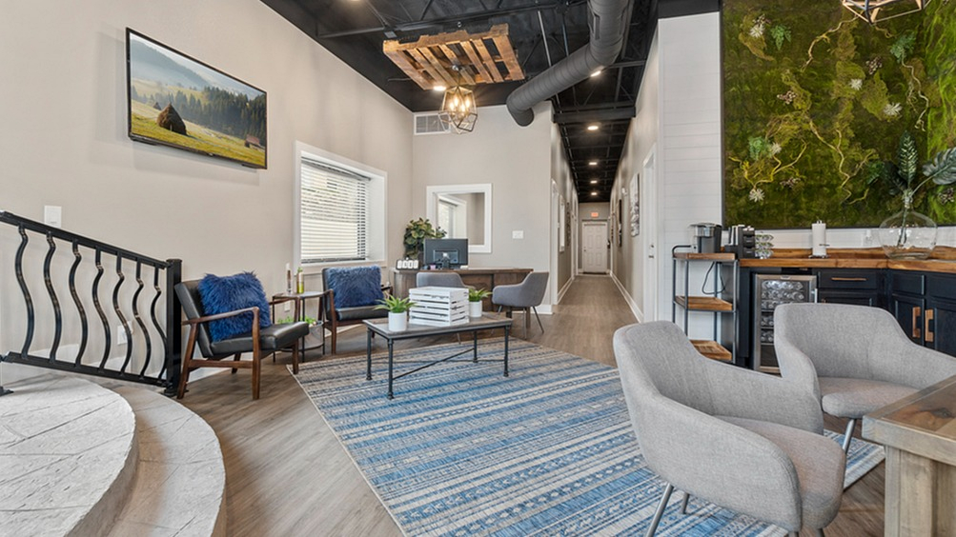 Inviting modern lounge area with stylish decor, featuring plush seating, a vibrant rug, and a unique green wall accent.