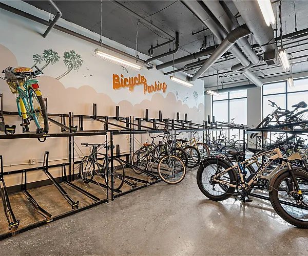 Modern bicycle parking area with ample racks, vibrant murals, and sleek design, offering convenient storage for residents.