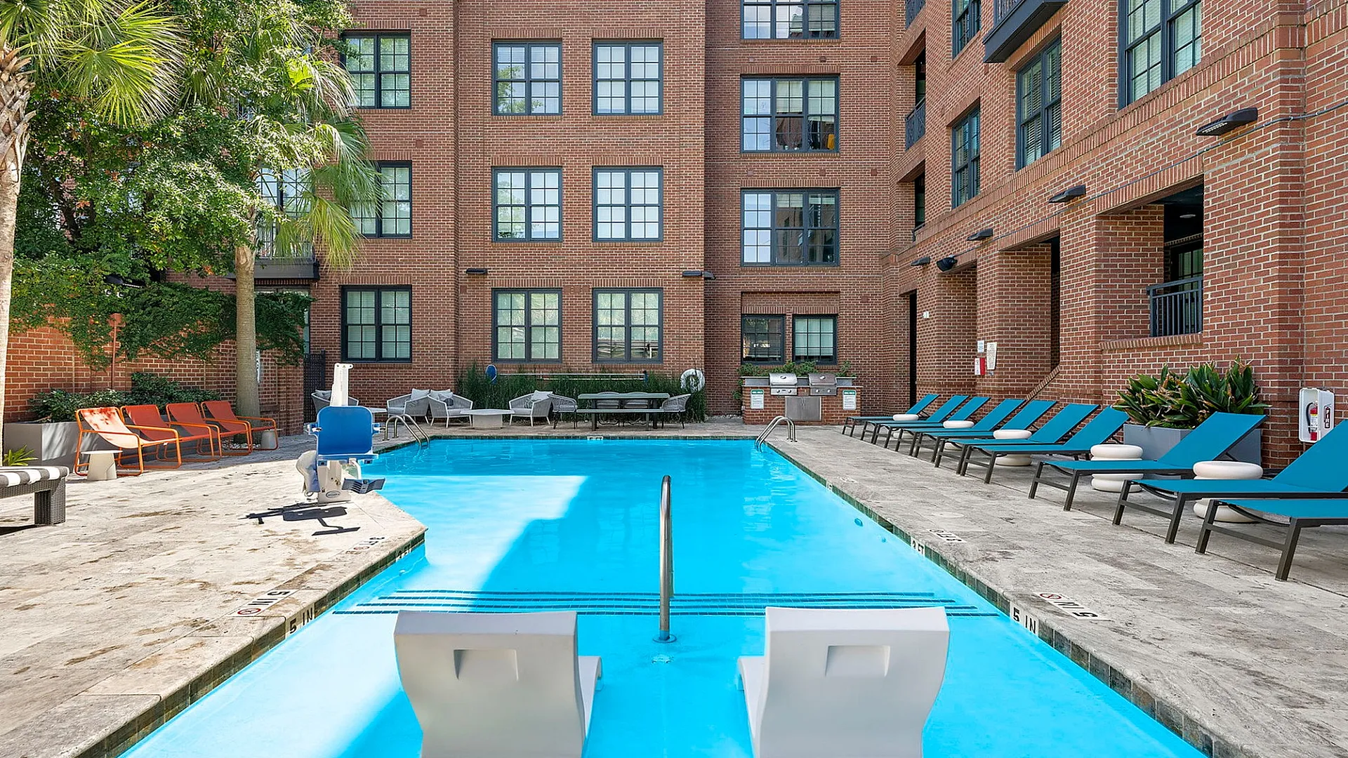 Chic urban apartment complex with a sparkling pool, stylish seating, and vibrant outdoor ambiance for relaxation.