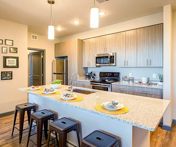 Modern kitchen with sleek cabinetry, granite countertops, and a stylish breakfast bar adorned with colorful place settings and contemporary stools.