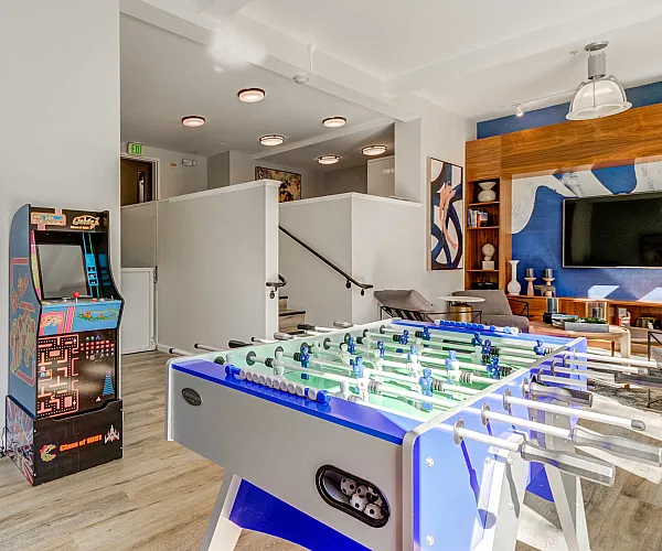Vibrant recreational room with vintage arcade games and a foosball table, perfect for entertainment and relaxation.