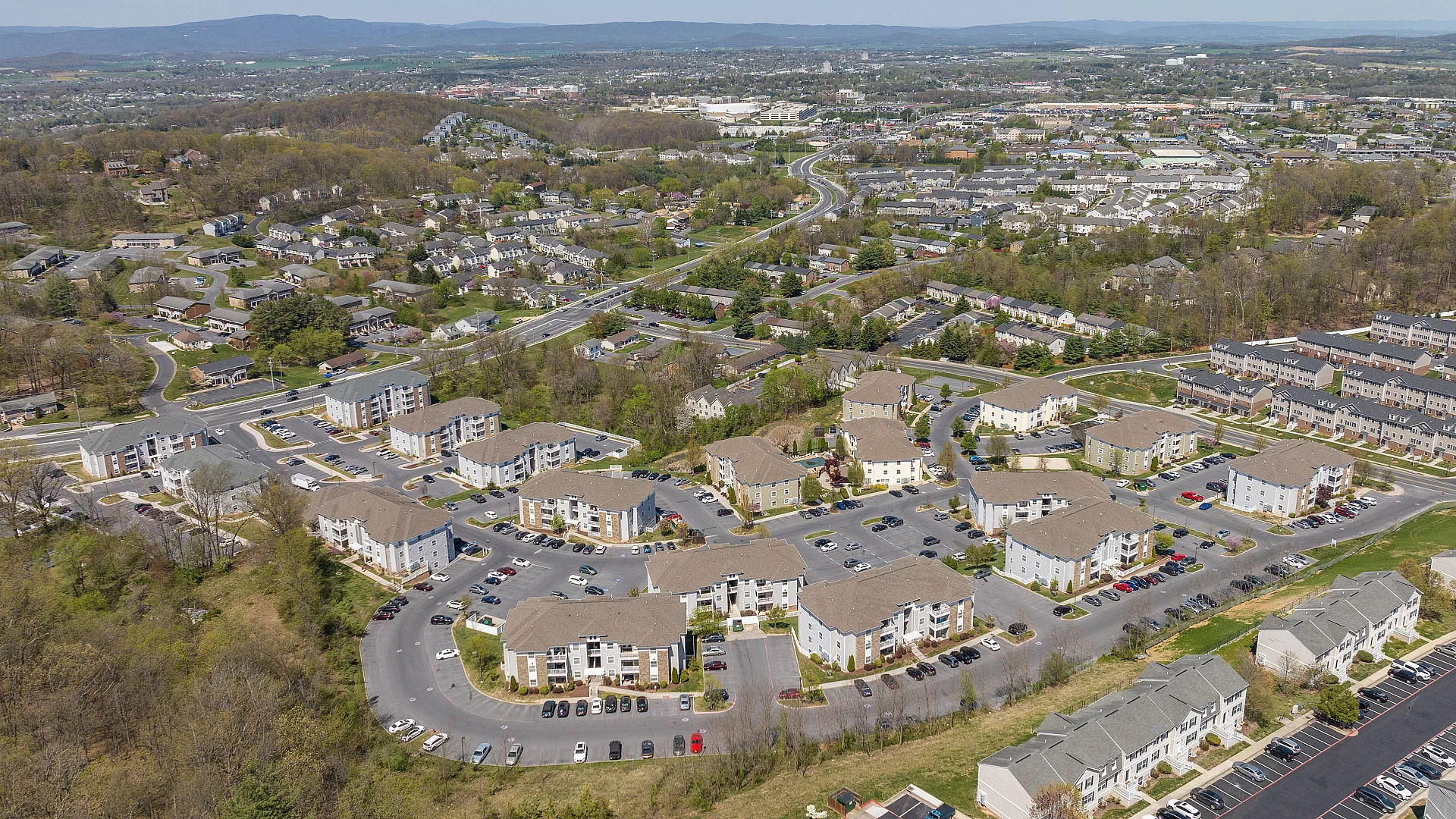 Scenic aerial view of a modern apartment complex nestled in a vibrant community with lush greenery and easy access to major roadways.