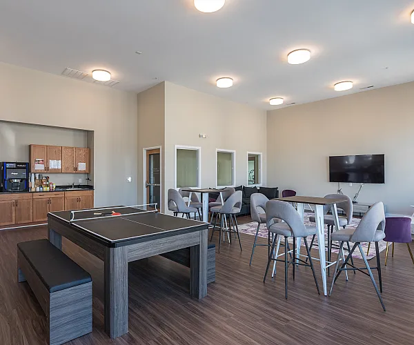 Modern communal lounge featuring a ping pong table, stylish seating, and a sleek entertainment area with a mounted TV.