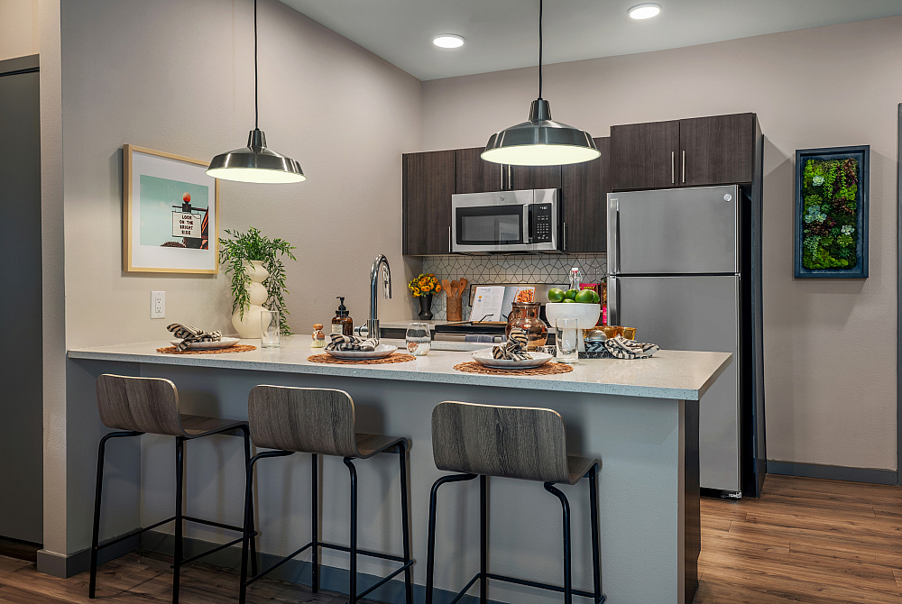 Modern kitchen with sleek stainless steel appliances, chic pendant lighting, and a cozy breakfast bar with seating for three.