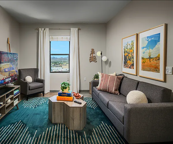 Inviting living room with modern gray sofa, vibrant artwork, and large window showcasing stunning mountain views.