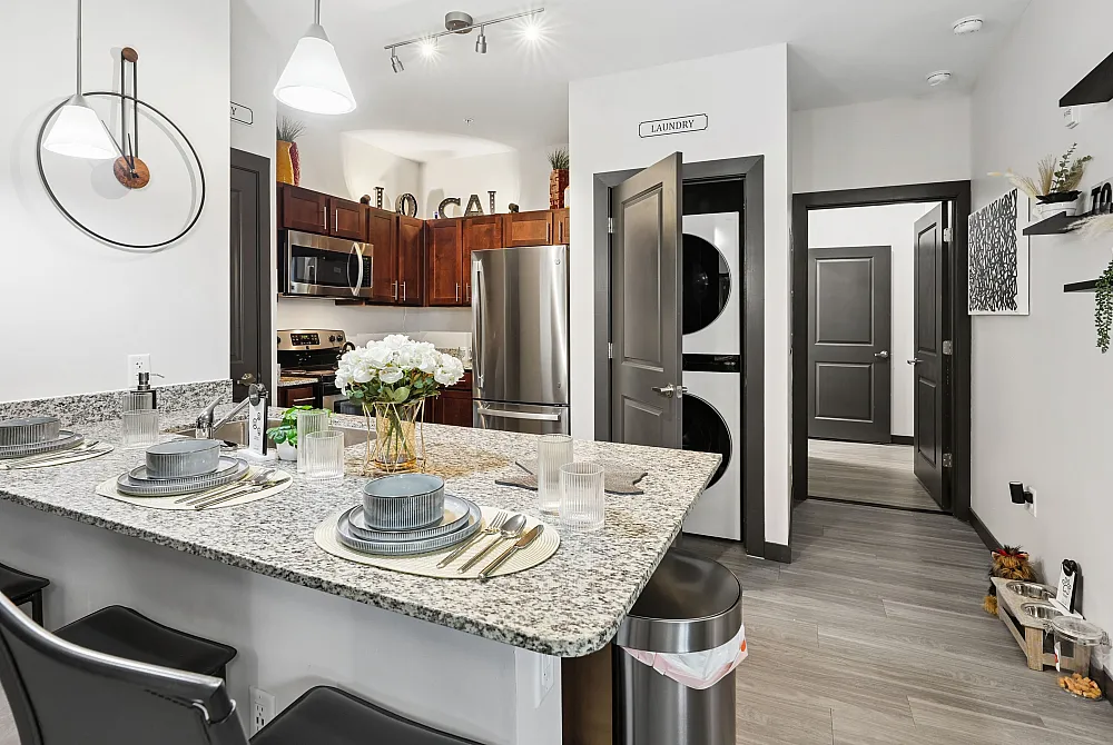 Contemporary kitchen with sleek granite countertops, polished appliances, and stylish dining setup, featuring a modern laundry area.