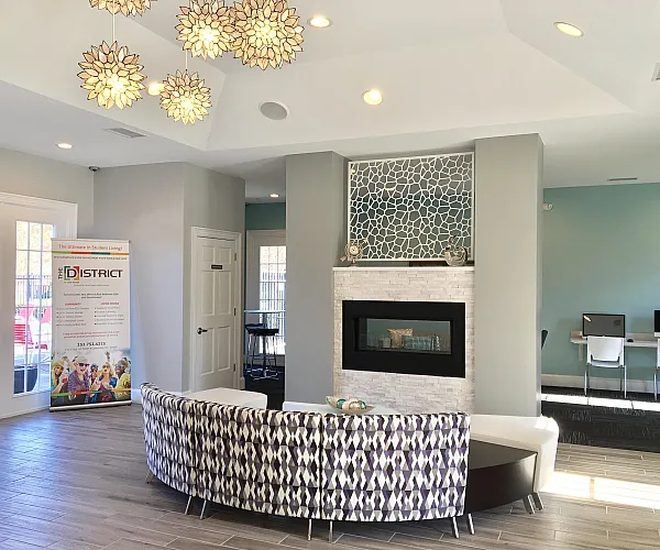 Modern living area featuring stylish pendant lights, a cozy fireplace, and a chic patterned sofa in a vibrant apartment lounge.