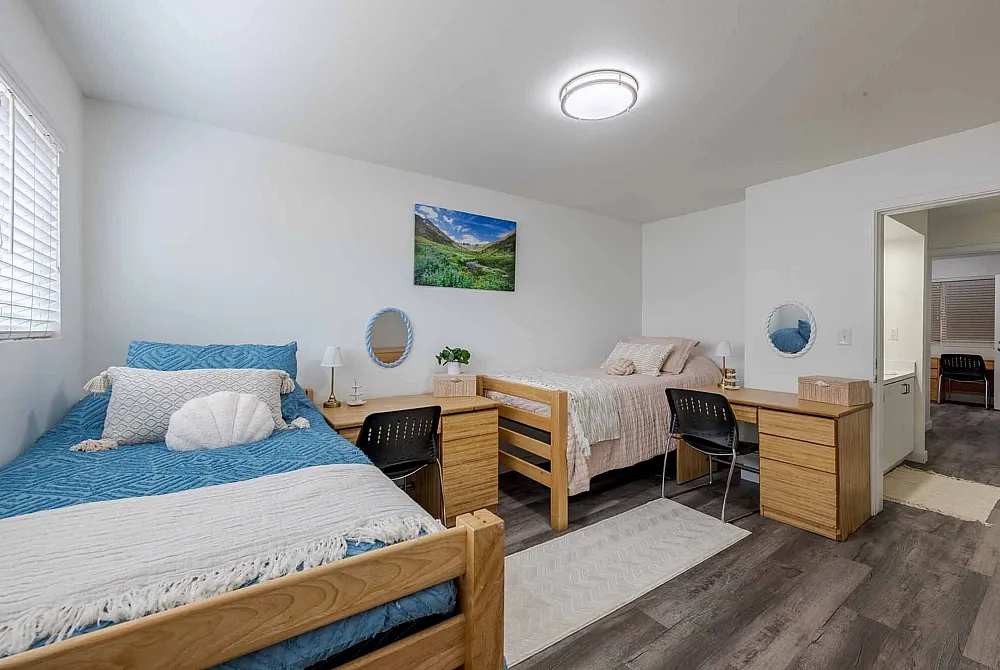 Inviting shared bedroom with two cozy single beds, bright decor, and natural light streaming through the window.