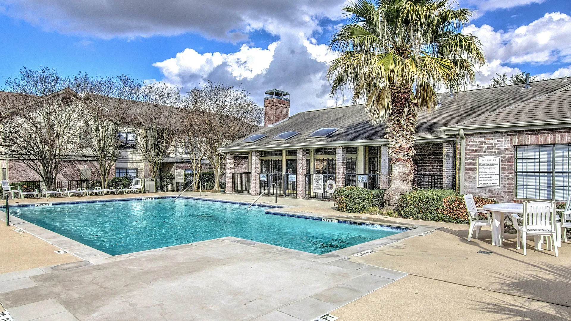 Inviting apartment community with a sparkling pool, sunlit patio, and palm tree accents, ideal for relaxation and leisure.