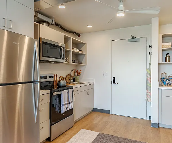 Contemporary kitchen featuring sleek stainless steel appliances, elegant open shelving, and stylish wood flooring.