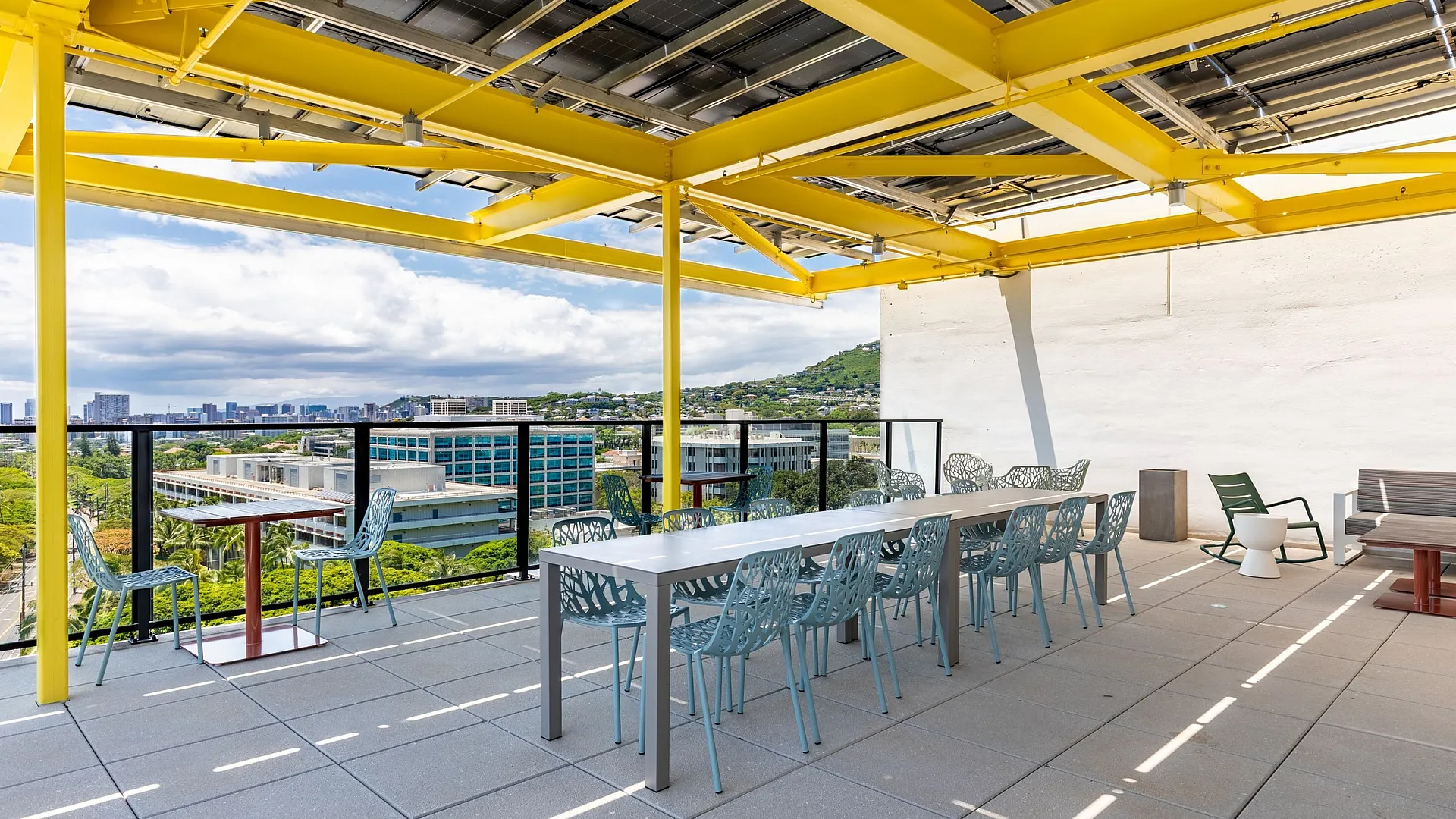 Inviting rooftop terrace with vibrant yellow beams, offering breathtaking city views and ample seating for outdoor gatherings.