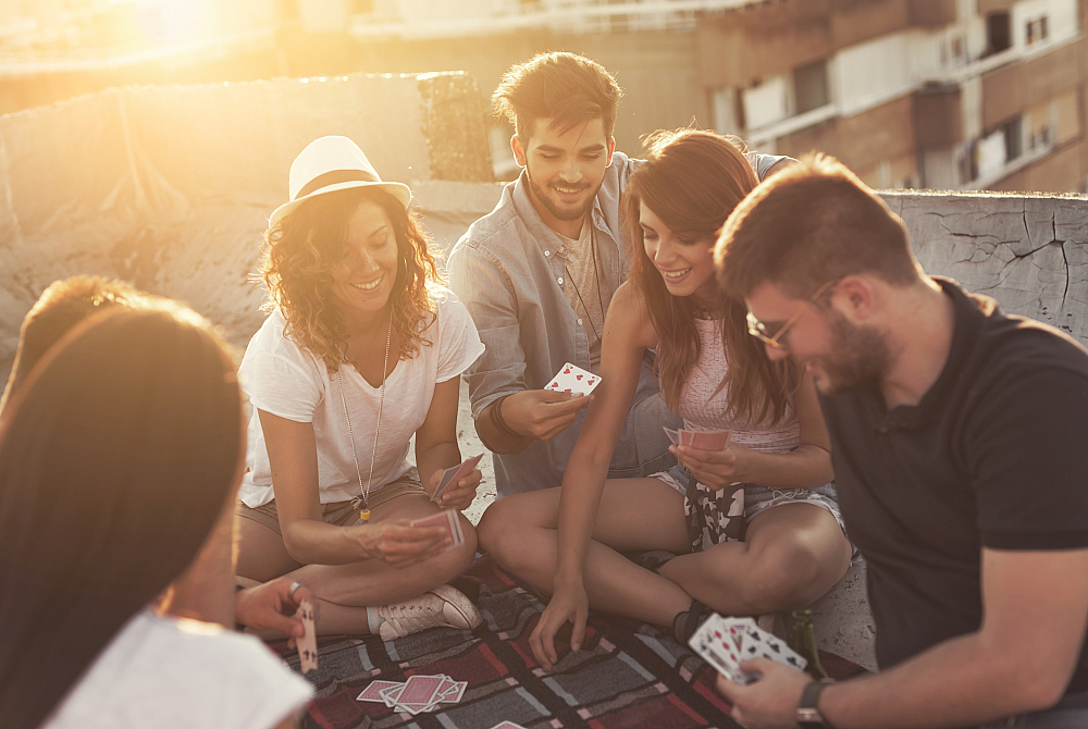 Vibrant group enjoying a card game on a sunny rooftop, creating a joyful and relaxed atmosphere.
