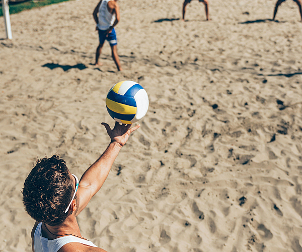 Dynamic beach volleyball scene showing a player serving with precision on a sunny sand court.