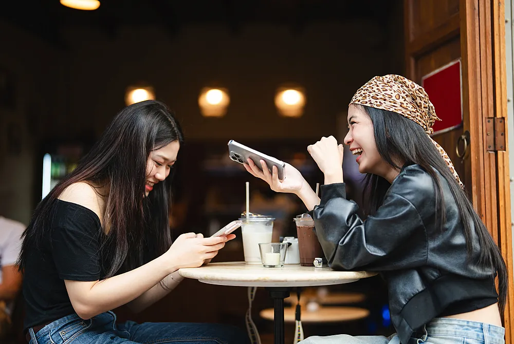 Two friends enjoying a lively conversation over drinks at a cozy cafe, with warm lighting and a welcoming atmosphere.