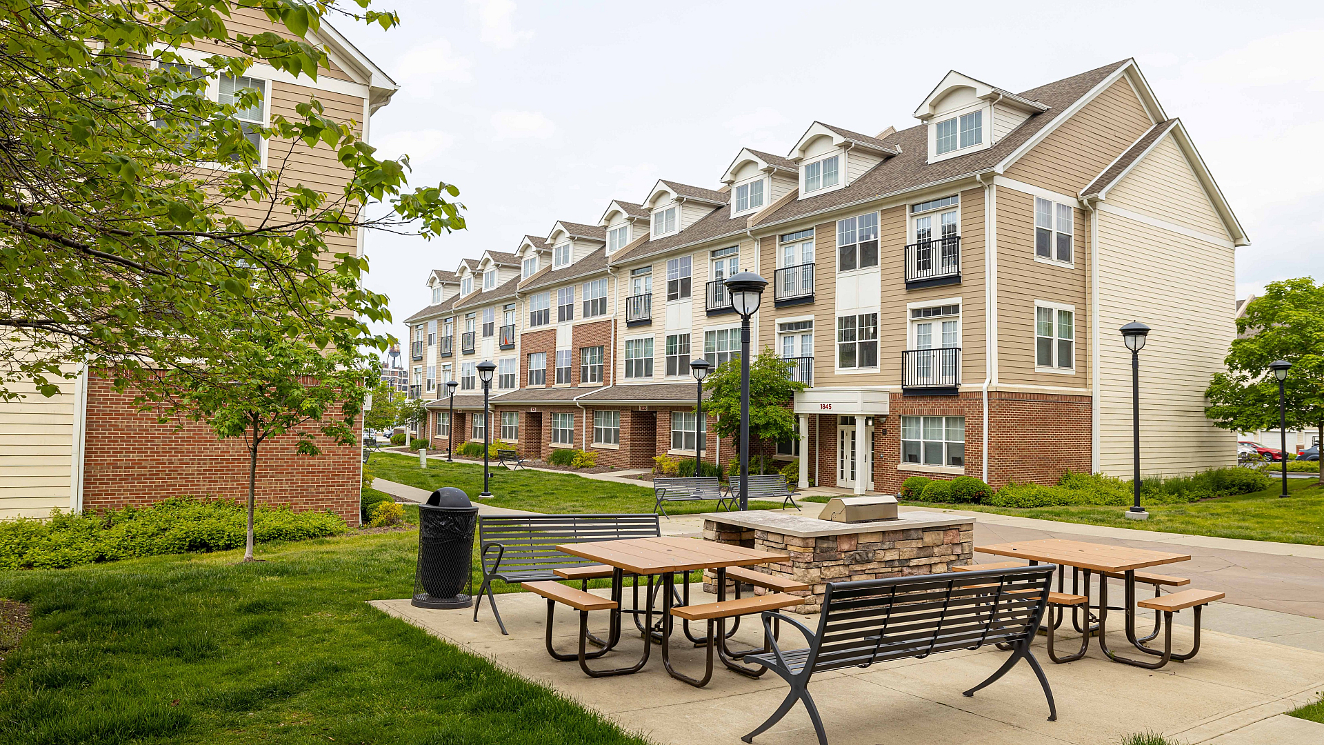 Charming modern apartment complex with lush greenery and inviting outdoor seating, perfect for relaxation and community gatherings.