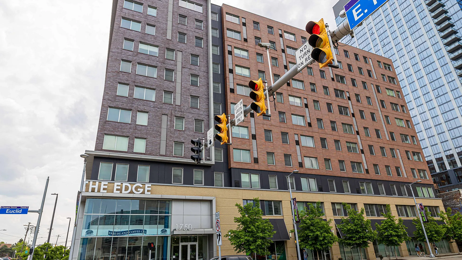 Modern urban apartment building, The Edge, with sleek architecture and vibrant street presence at busy intersection.