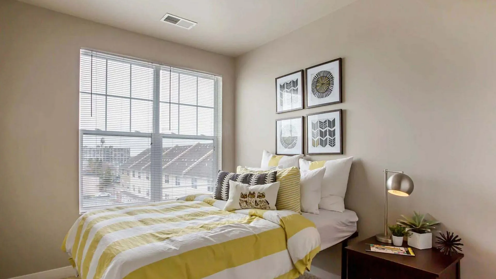 Cozy bedroom featuring modern decor, a plush bed with striped bedding, ample natural light from large windows, and stylish wall art.