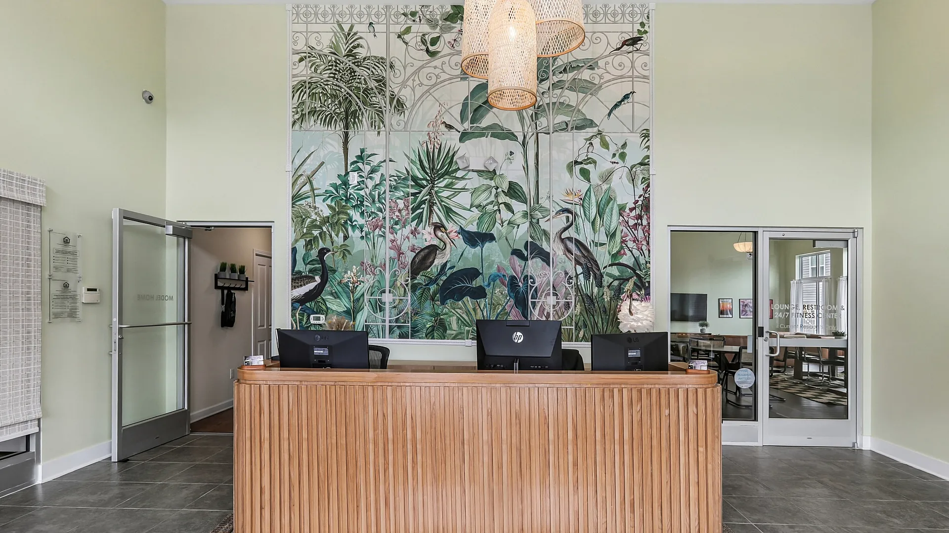 Elegant apartment lobby featuring a stylish wooden reception desk and vibrant nature-themed mural, creating a welcoming atmosphere.