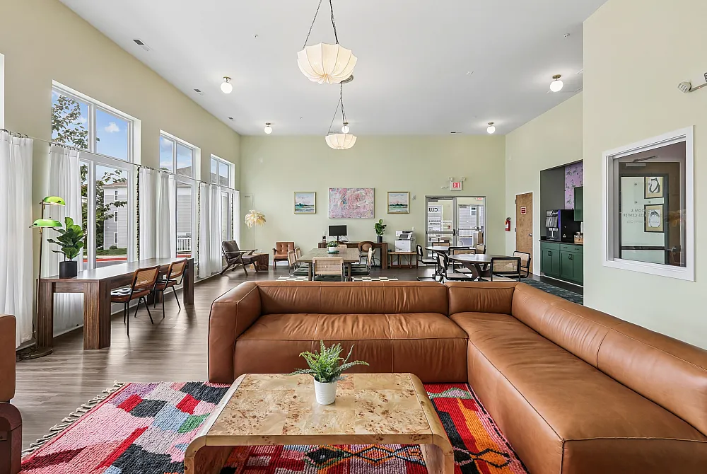 Spacious and inviting common area featuring modern leather seating, vibrant artwork, and large windows with abundant natural light.