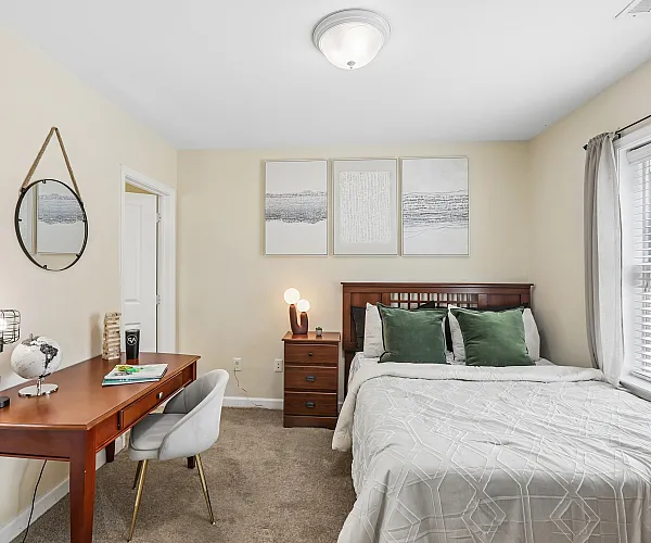 Charming and cozy bedroom featuring elegant wooden furniture, stylish wall art, and abundant natural light from large windows.