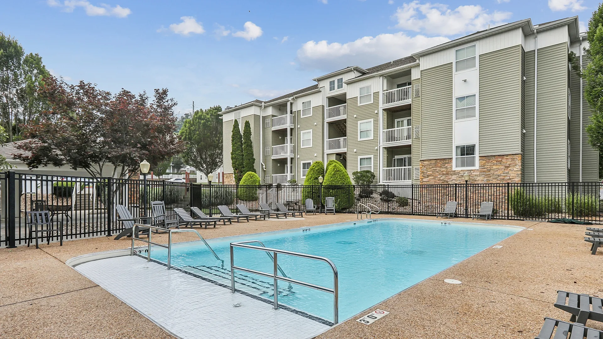 Charming residential apartment complex featuring inviting pool area with luxurious lounge chairs, surrounded by lush greenery and modern architecture.