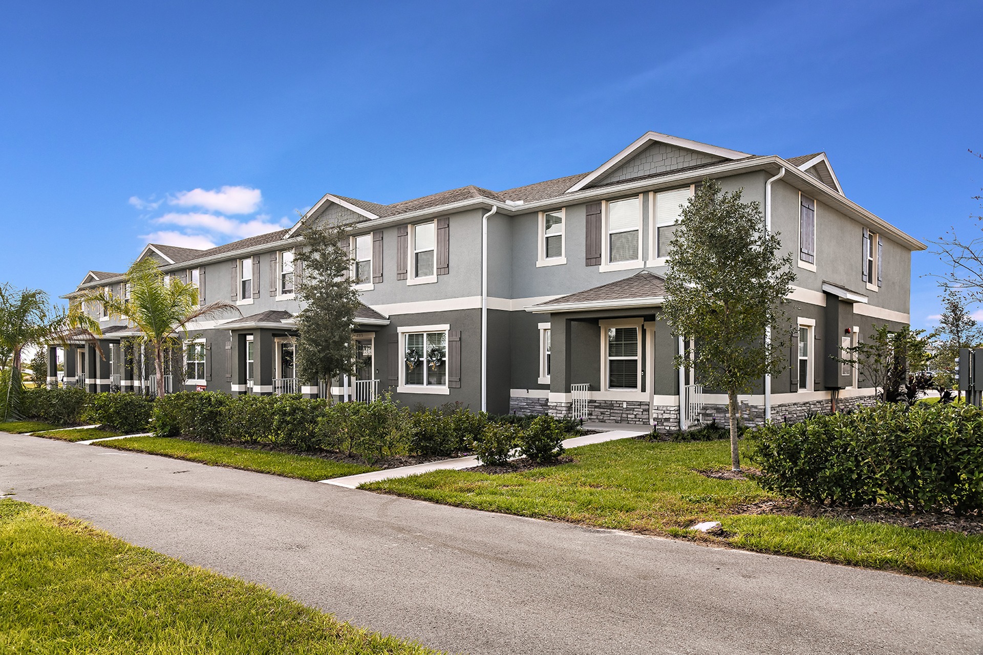Two story homes at Summerwell Avian Pointe in Apopka, FL, featuring a grey exterior and grassy lawn.
