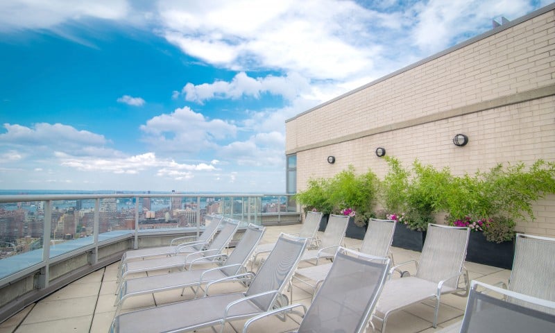 Rooftop lounge at our apartments for rent in Flatiron, featuring beach chairs and a view of the New York skyscrapers.