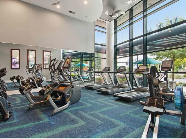 Fitness center at our apartments for rent in Atlanta, featuring treadmills, exercise bikes, and carpeted flooring.
