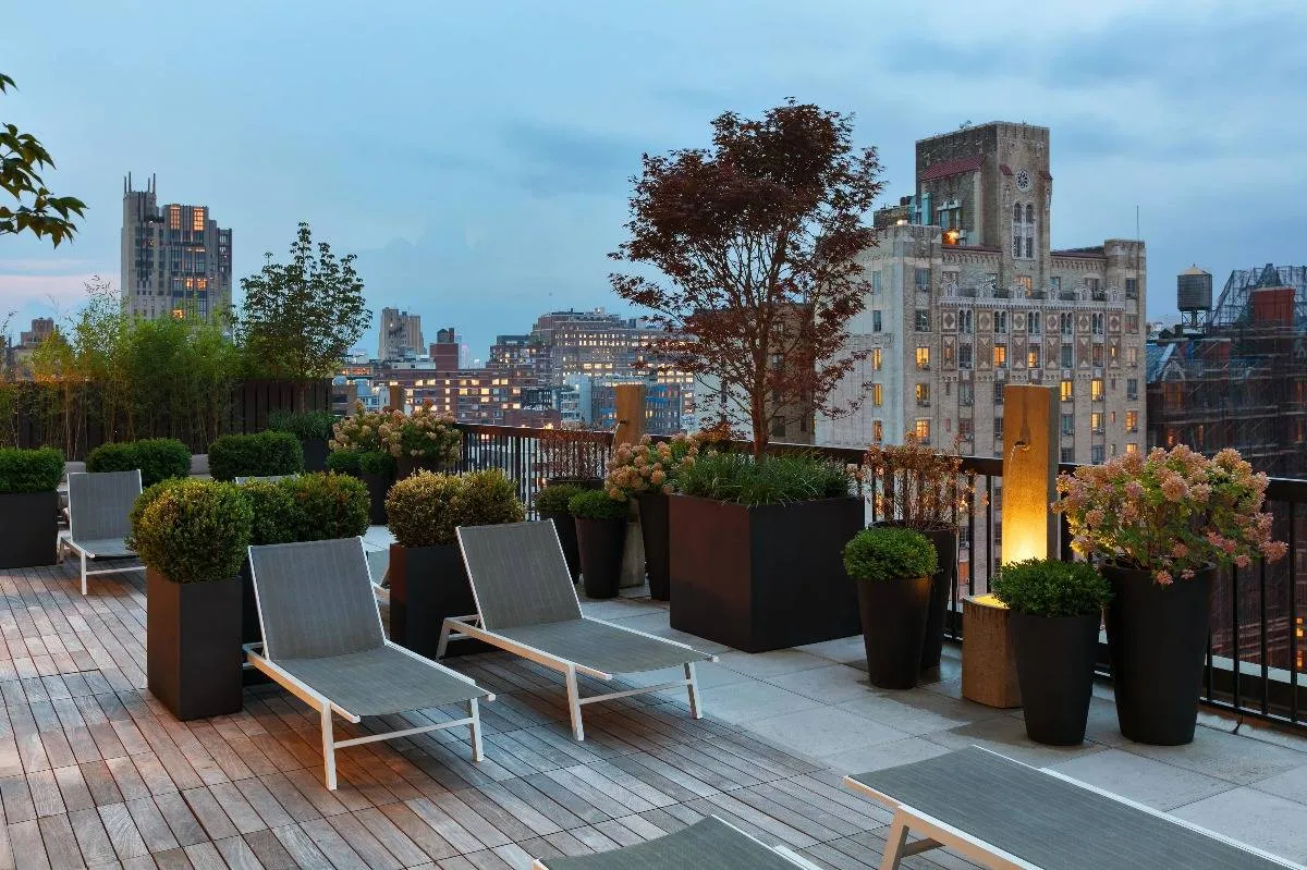 The deck lounge at our apartments in New York, featuring reclining chairs, potted plants, and a view of the city.