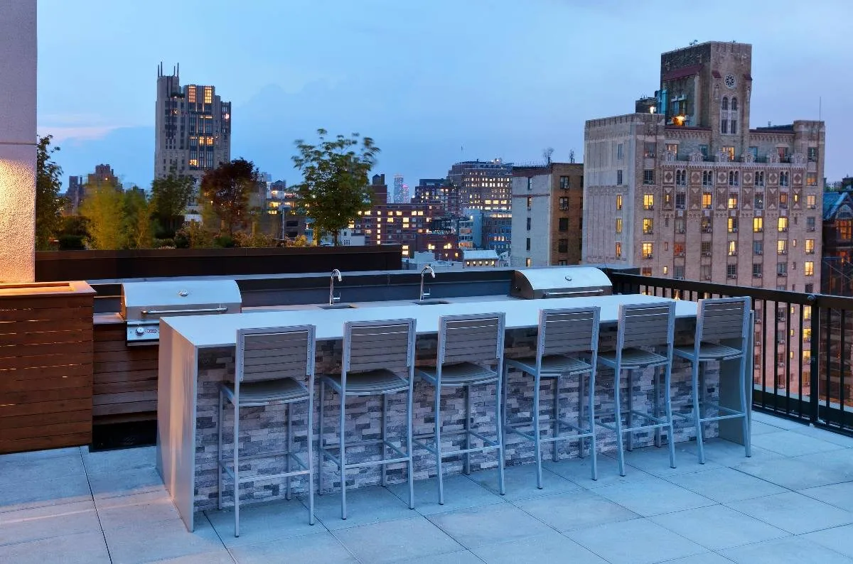 Outdoor lounge at our apartments in Chelsea, featuring counter seating, grill stations, and a view of the city.
