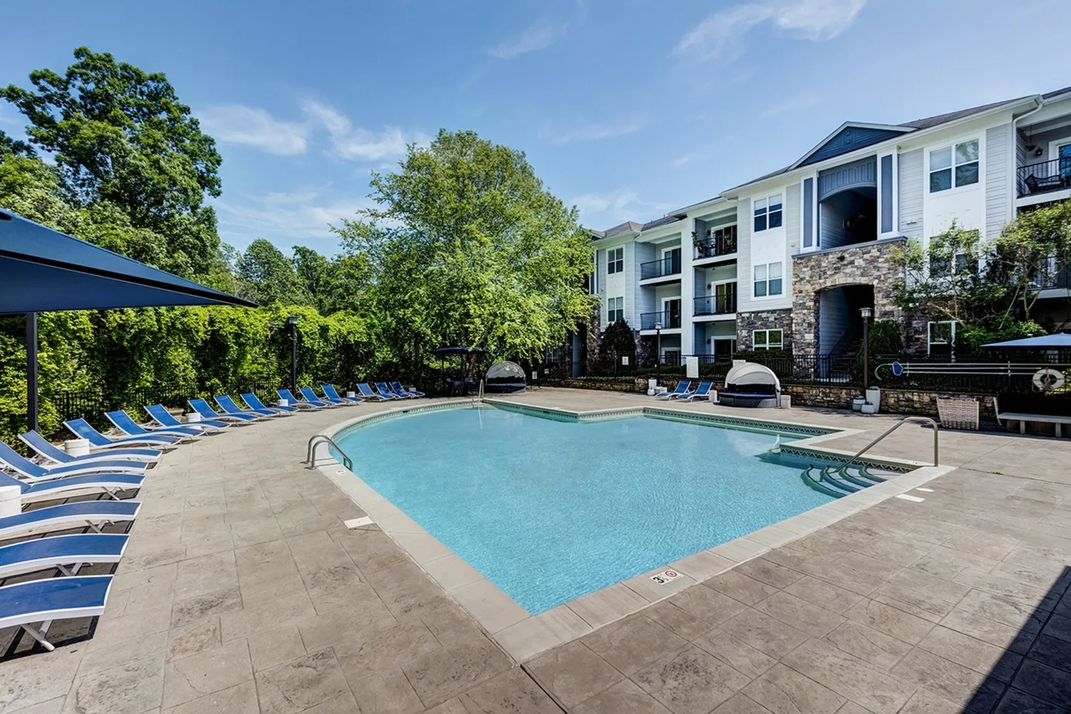 Pool and lounge seating surroundedby trees