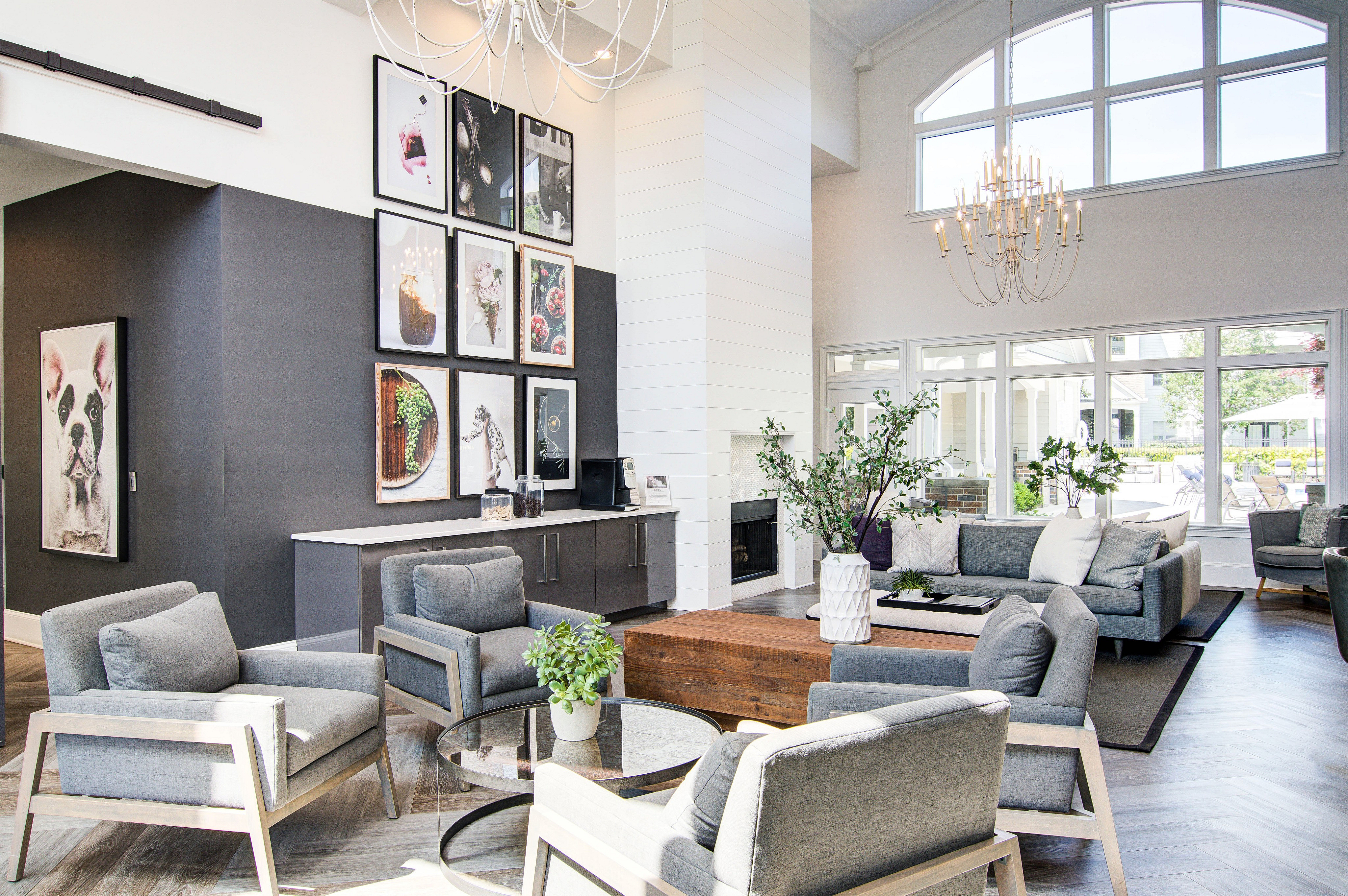 Elegant living area featuring modern gray furniture, vibrant artwork, and large windows with natural light.