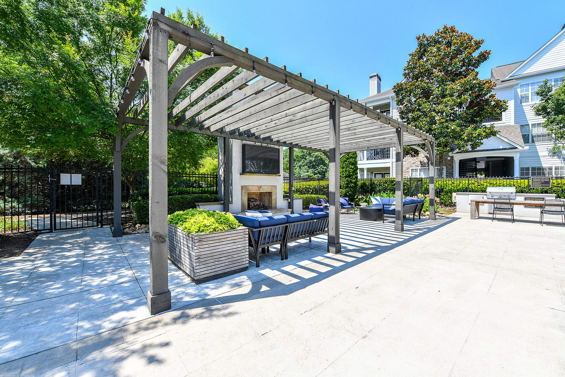 Chic outdoor lounge area featuring a stylish pergola, cozy seating, and a modern fireplace, ideal for relaxation and entertainment.