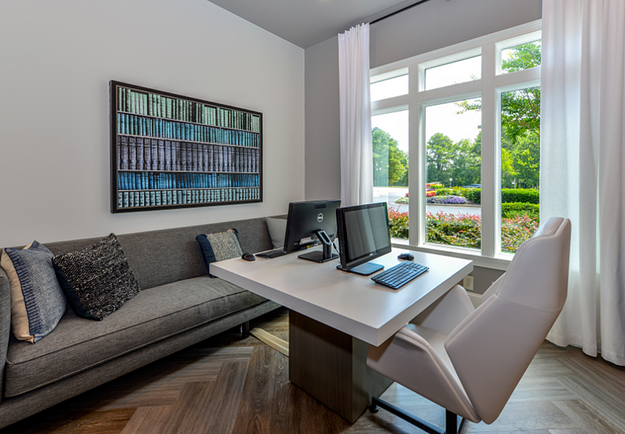 Elegant home office with modern desk, comfortable seating, and large window with lush garden view.