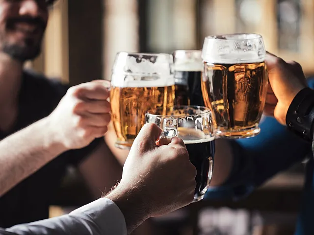 Joyful gathering with friends clinking beer glasses in a cozy setting.