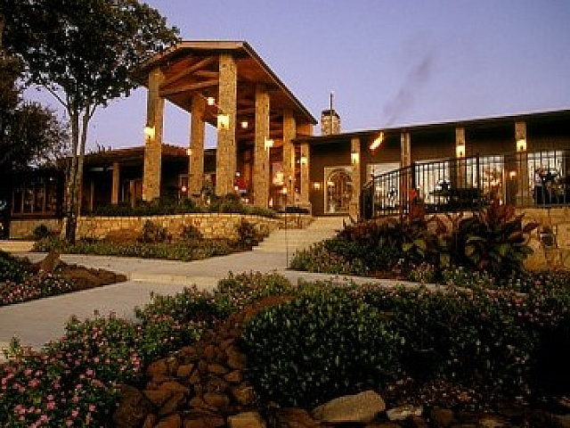 Charming lodge-style building with a rustic stone design, warm outdoor lighting, and lush landscaping for a serene and inviting ambiance.