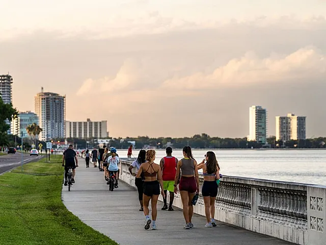 Vibrant waterfront promenade with joggers and cyclists enjoying a scenic city skyline view at sunset.