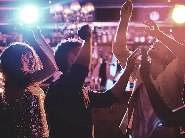Vibrant nightclub scene with people joyfully dancing under colorful lights.