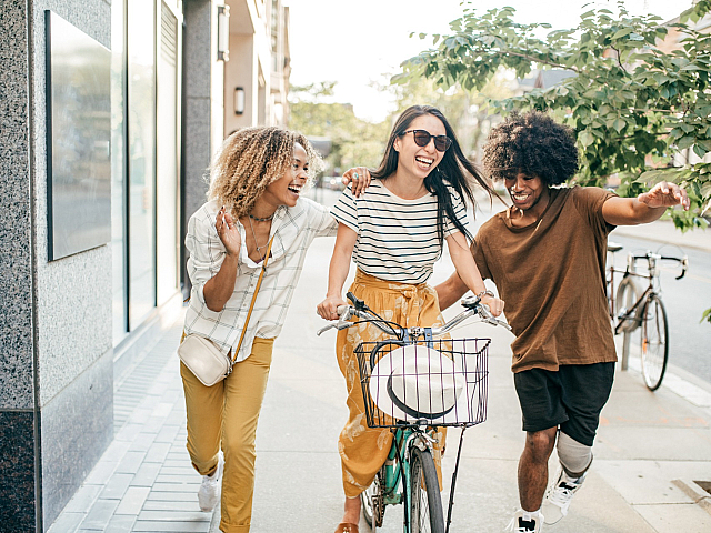 Vibrant urban scene with three friends enjoying a sunny day with a bicycle, embodying youth and energy on a city street.