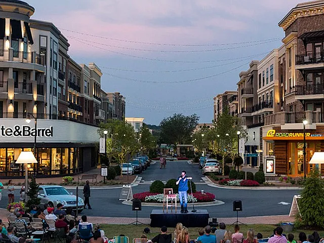 Charming urban plaza with elegant apartment buildings, bustling shops, and vibrant community gathering at dusk.